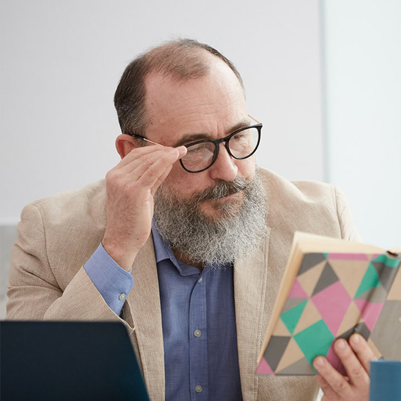 man adjusting glasses and reading